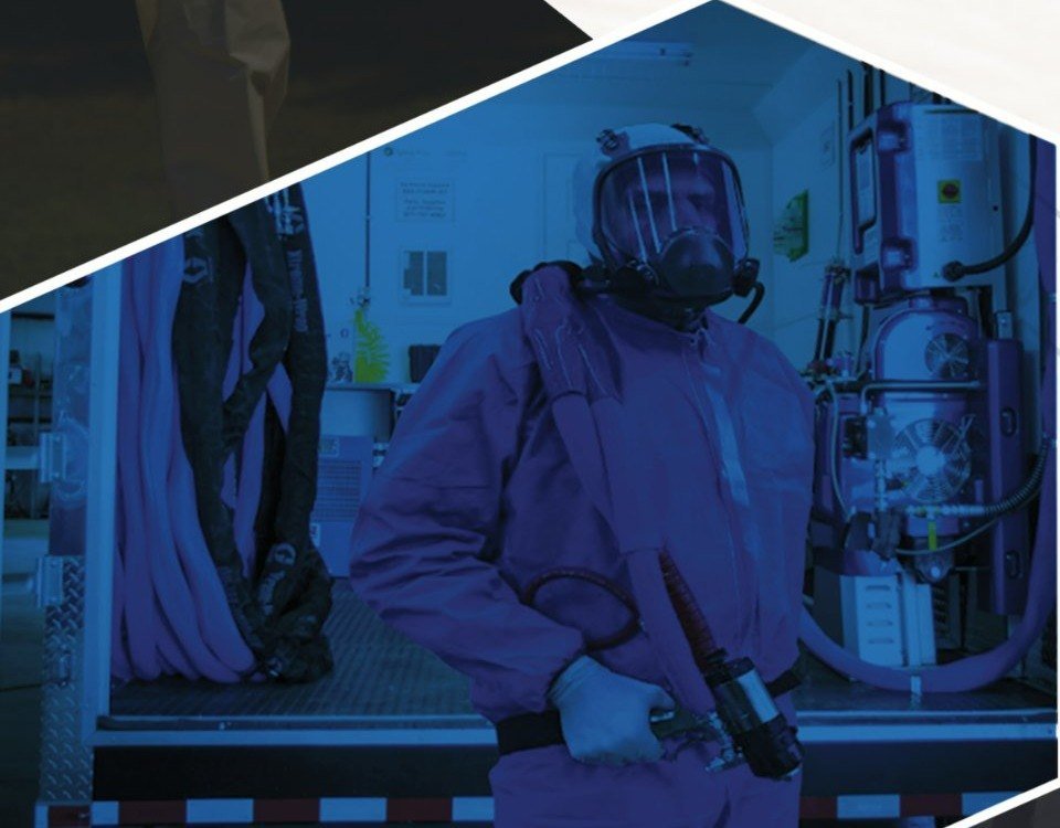 ArmorThane applicator in full protective gear beside a mobile spray rig